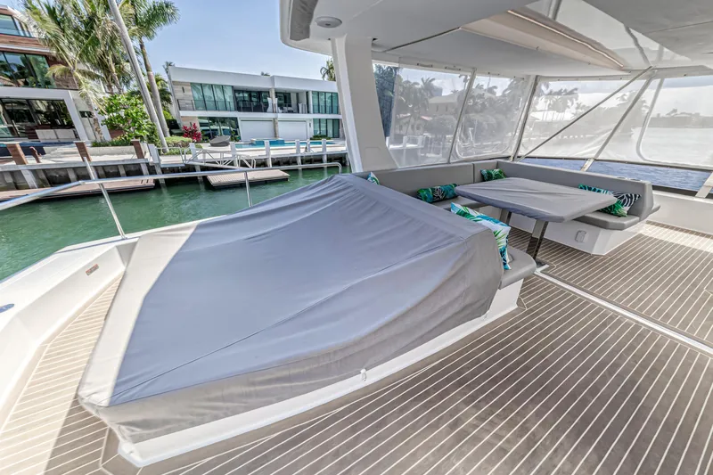 Double Feature Yacht Photos Pics 2023 Leopard 53 Powercat deck with covered seating and table, dockside view.