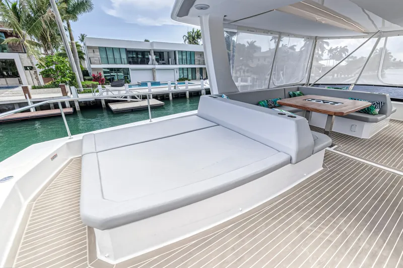 Double Feature Yacht Photos Pics 2023 Leopard 53 Powercat yacht with spacious deck and seating area, docked by waterfront homes.