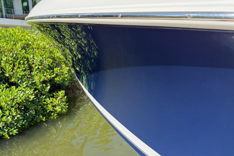  Yacht Photos Pics 2024 Pursuit S 248 Sport boat hull reflecting greenery by the water.