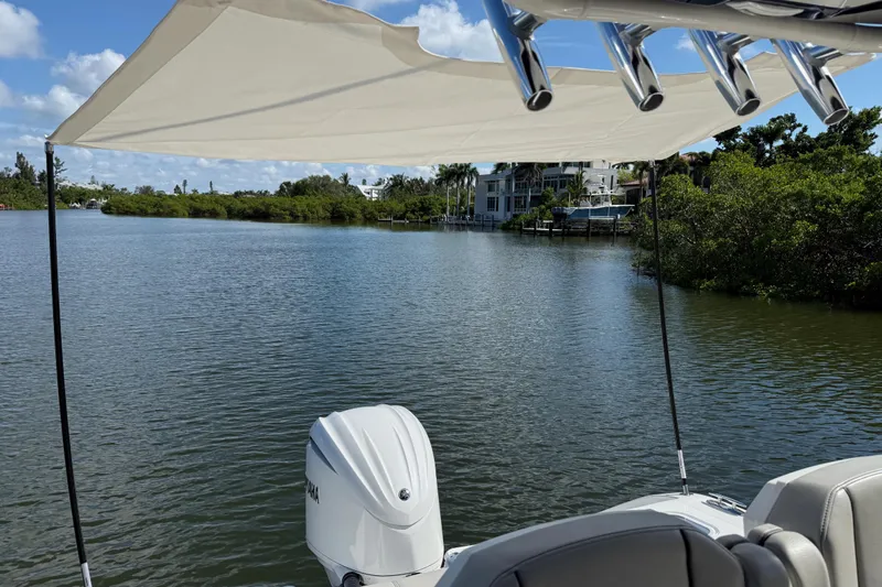  Yacht Photos Pics 2024 Pursuit S 248 Sport boat on calm water, featuring a sunshade and outboard motor.