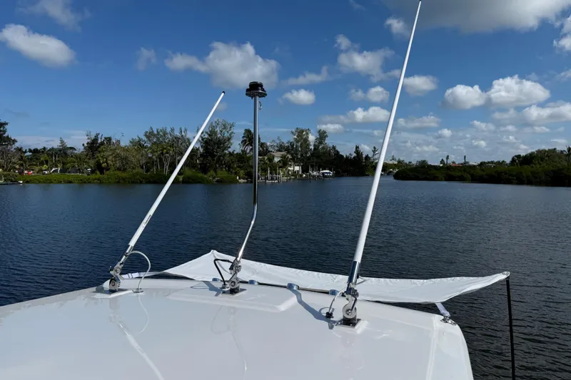  Yacht Photos Pics 2024 Pursuit S 248 Sport boat on a serene lake under a blue sky.