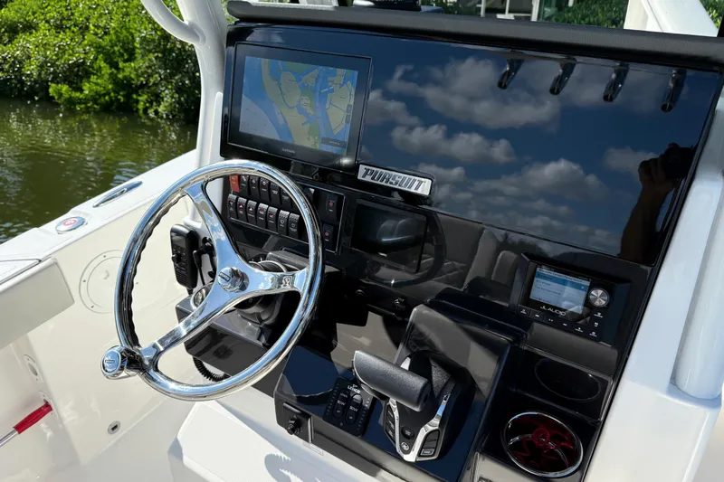  Yacht Photos Pics 2024 Pursuit S 248 Sport boat dashboard with steering wheel and navigation display.