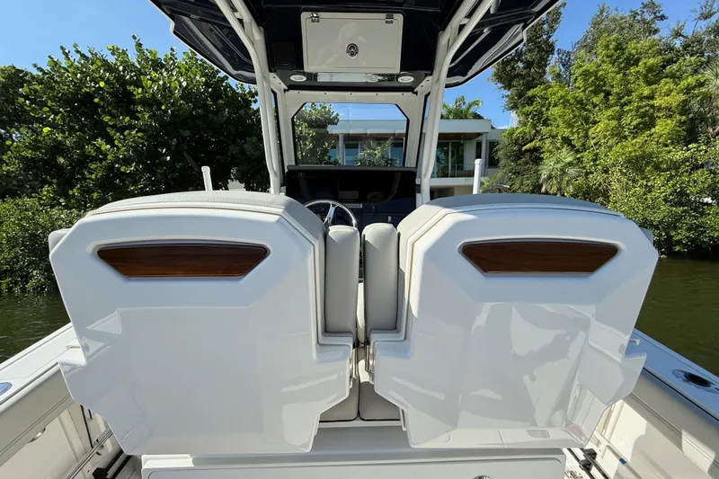  Yacht Photos Pics 2024 Pursuit S 248 Sport boat interior with dual seats, lush greenery background.