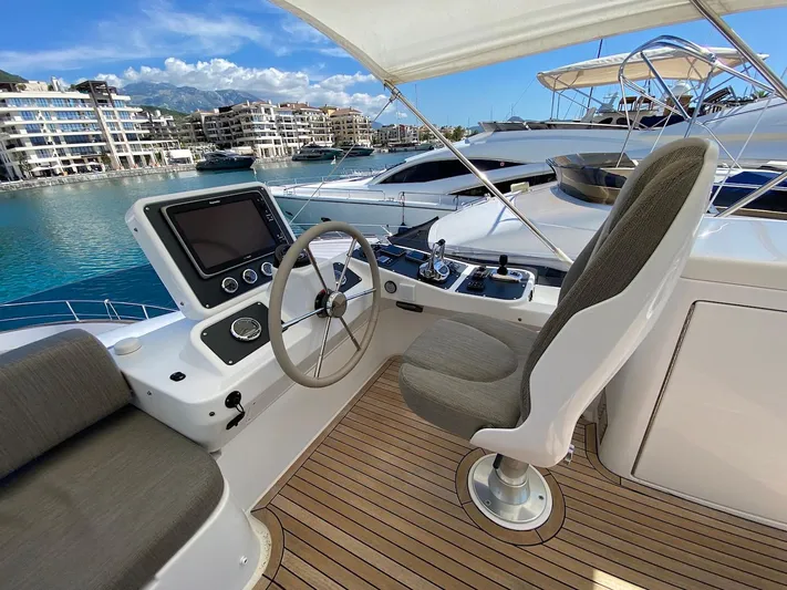 Mizar Yacht Photos Pics Helm of 2017 Azimut Magellano 53 yacht with modern controls, docked in a marina.