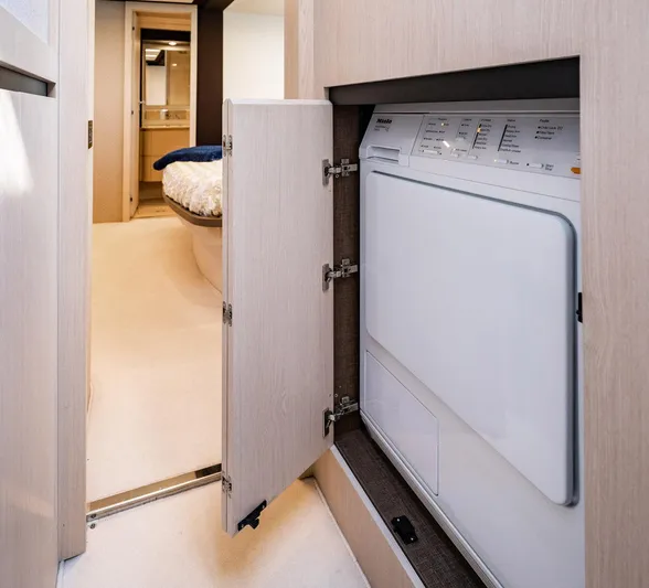 Amici Yacht Photos Pics Laundry area inside 2017 Azimut 66 yacht, featuring a built-in washing machine.