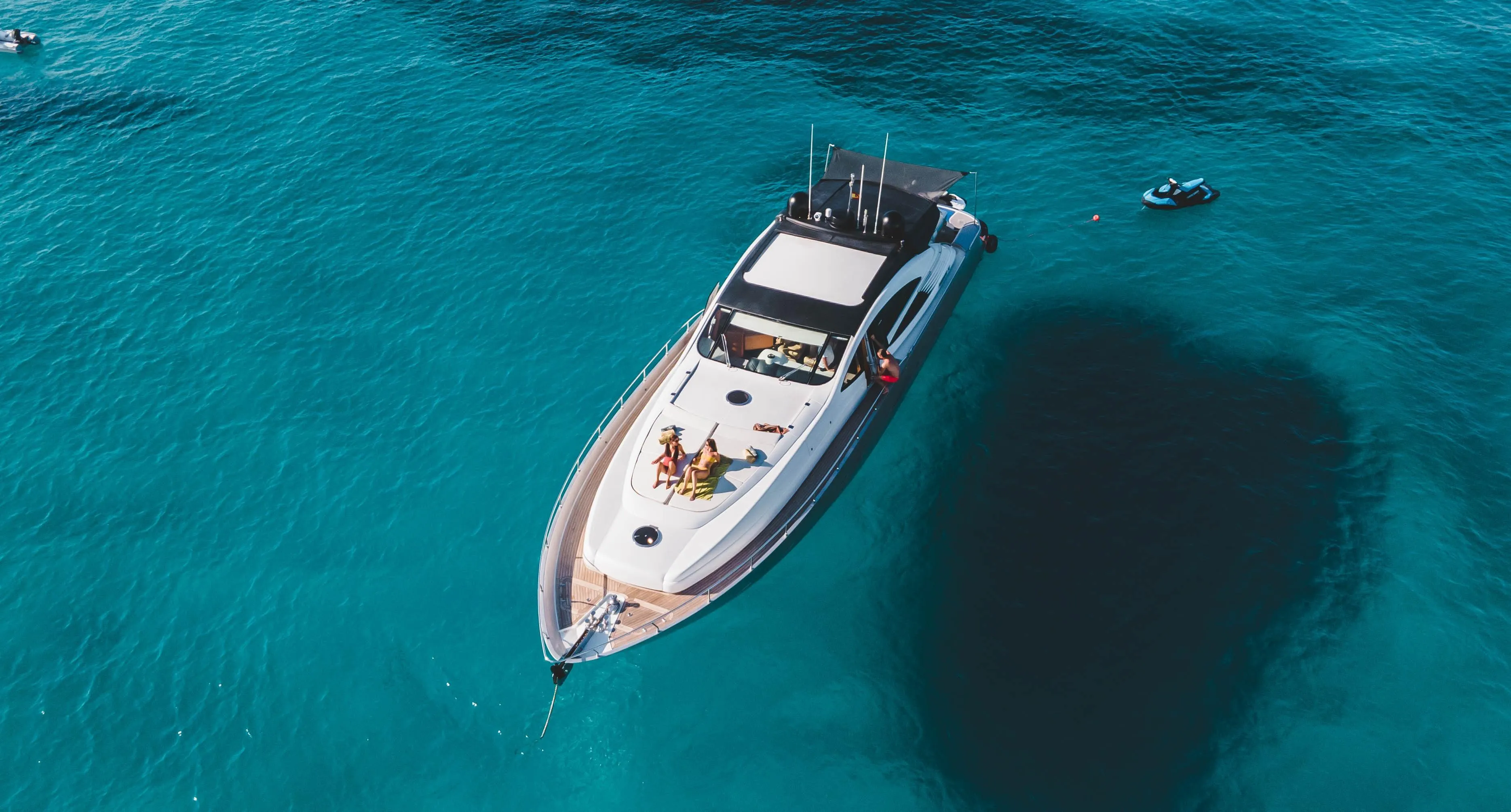 Luxury Pershing 76 yacht from 2005 on clear blue water, aerial view.