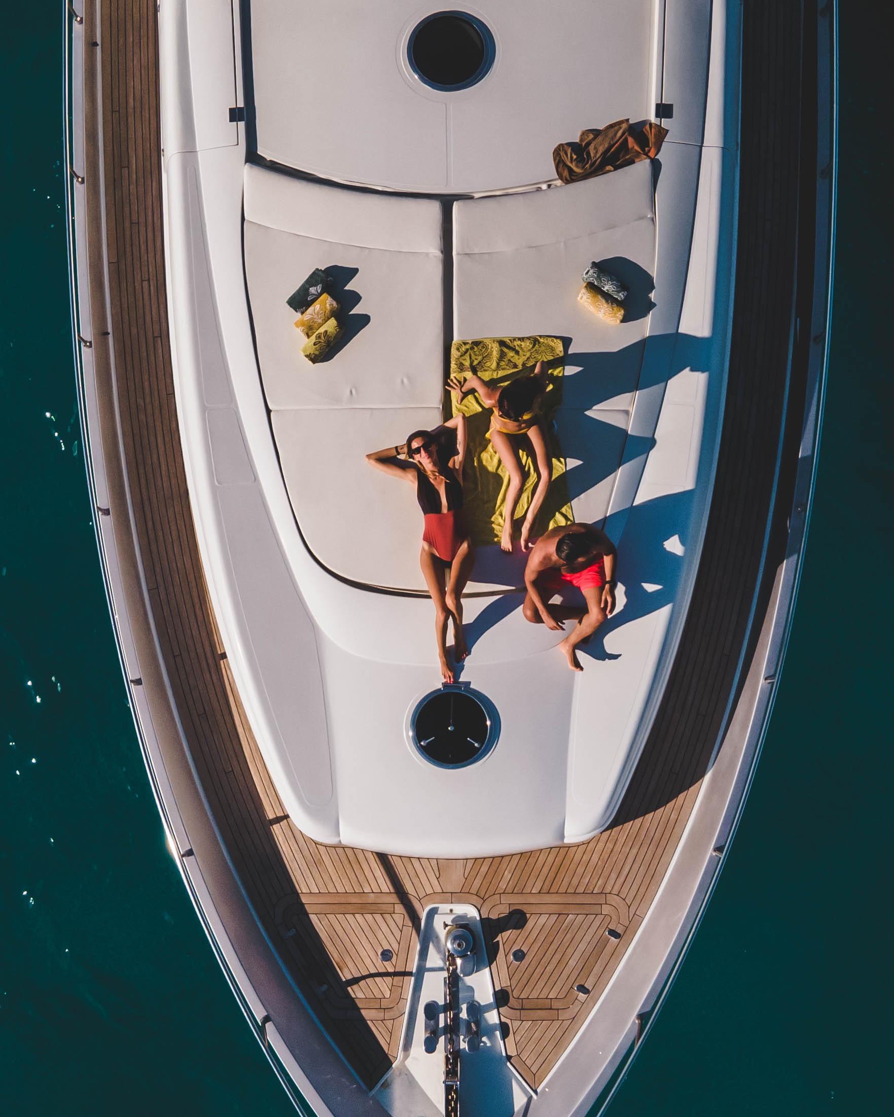 Aerial view of people sunbathing on a 2005 Pershing 76 yacht deck.