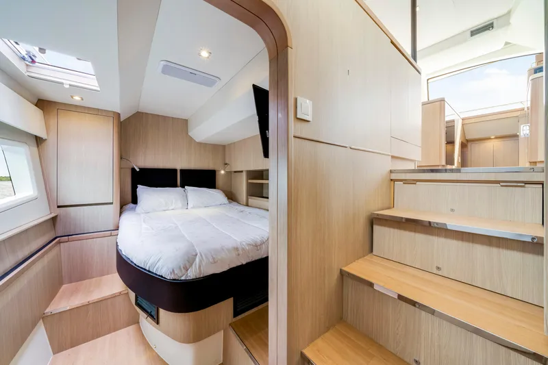 Altair Yacht Photos Pics Luxurious interior of 2019 Aquila 44 Yacht featuring a cozy bedroom and wooden stairs.
