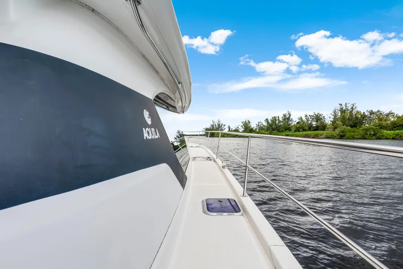 Altair Yacht Photos Pics Aquila 44 Yacht 2019 cruising on a serene river under a clear blue sky.