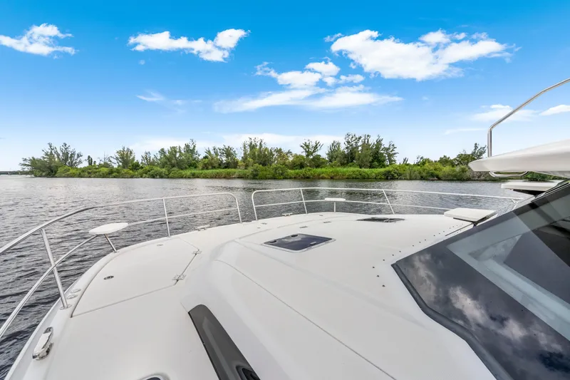 Altair Yacht Photos Pics 2019 Aquila 44 Yacht cruising on a serene river under a clear blue sky.