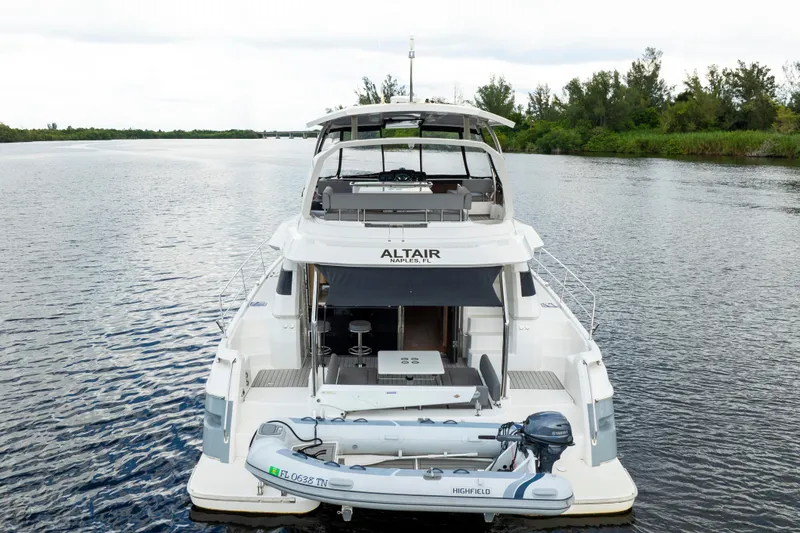 Altair Yacht Photos Pics 2019 Aquila 44 Yacht on calm water, featuring a small dinghy at the stern.