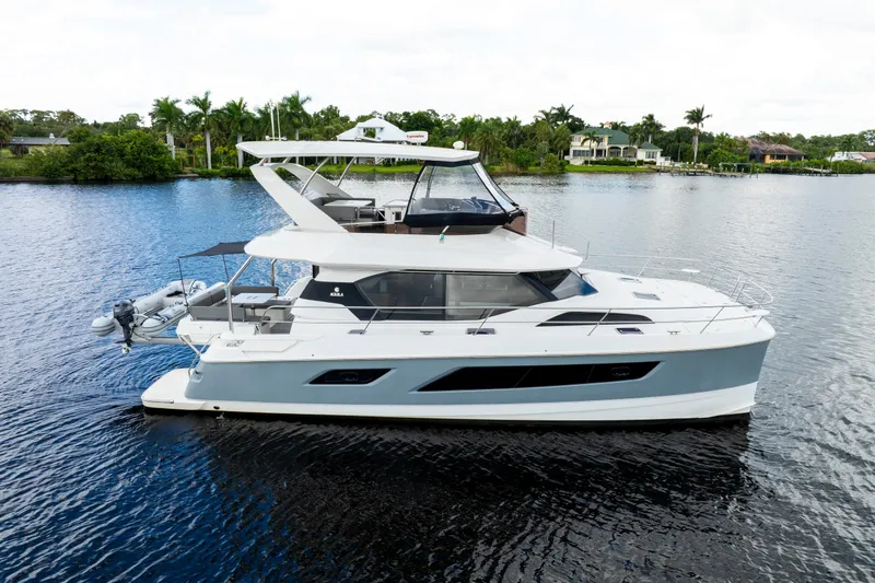 Altair Yacht Photos Pics 2019 Aquila 44 Yacht cruising on a serene waterway with lush greenery in the background.