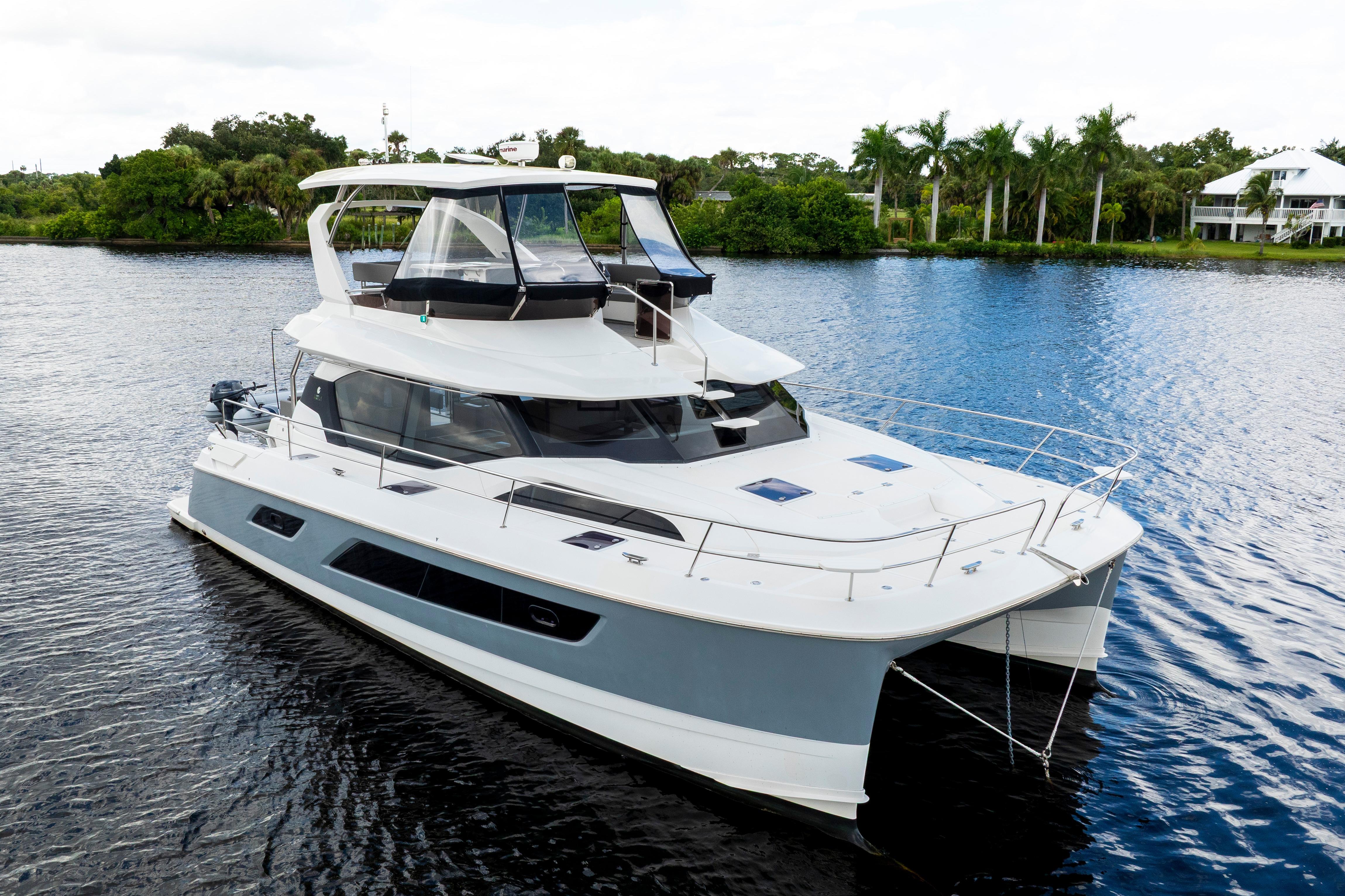 2019 Aquila 44 Yacht cruising on a serene river with lush greenery.