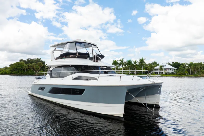 Altair Yacht Photos Pics 2019 Aquila 44 Yacht on calm water with lush greenery and blue sky.