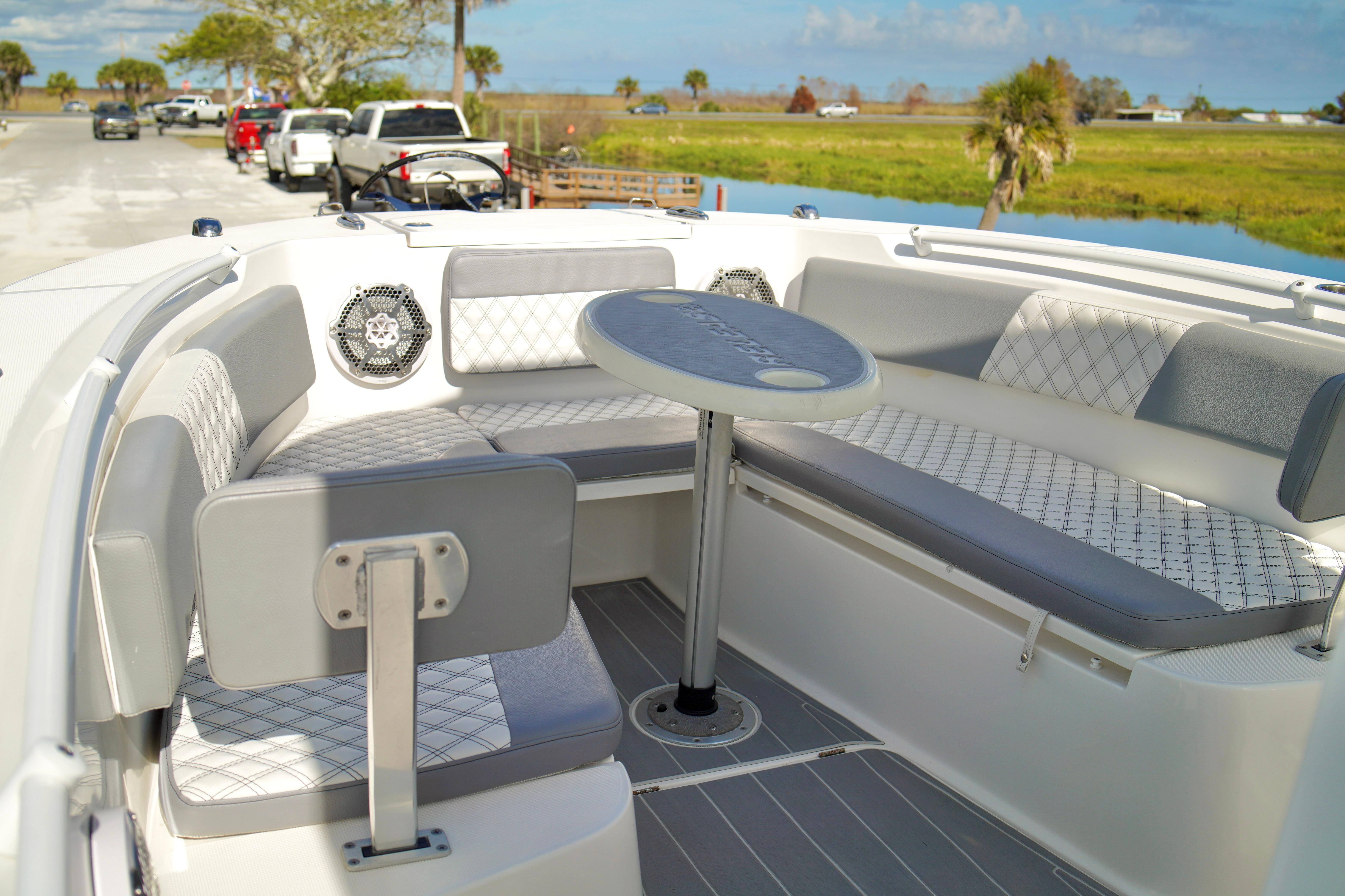 2017 Release 240 RX boat interior with cushioned seating and table, parked near a scenic waterway.