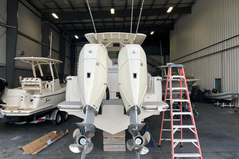 Zippy Yacht Photos Pics 2026 Scout 330 LXF boat in a warehouse with dual outboard engines.