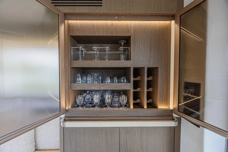  Yacht Photos Pics Luxurious glassware cabinet on 2022 Azimut Magellano 66 yacht, featuring elegant lighting and wood finish.
