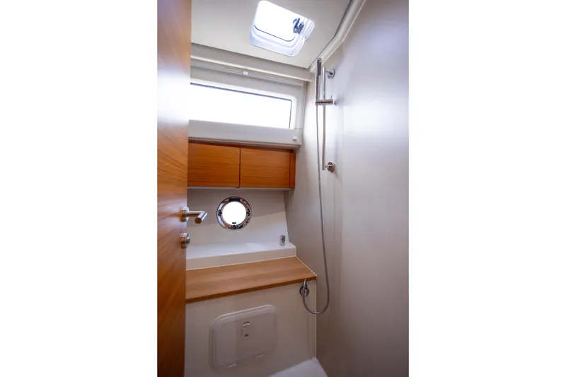 Tui Yacht Photos Pics 2023 Greenline 48 Fly yacht bathroom with wooden cabinetry and porthole window.