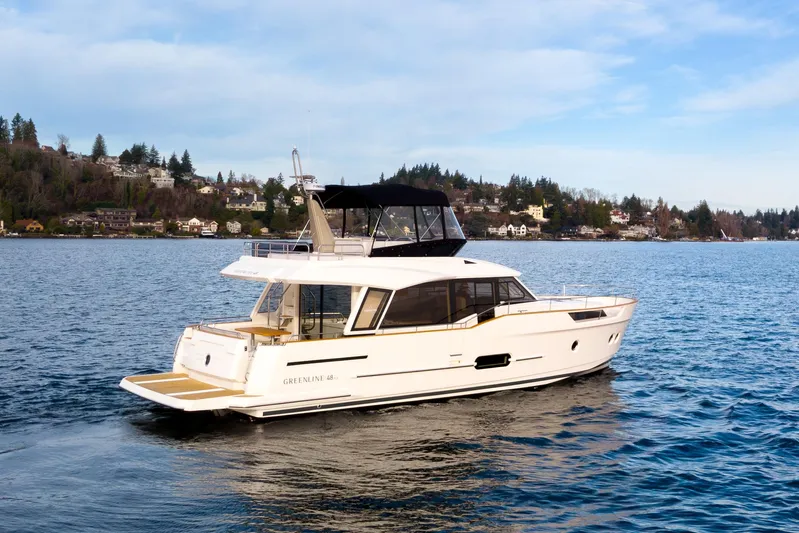 Tui Yacht Photos Pics 2023 Greenline 48 Fly yacht cruising on a scenic lake with hillside homes.