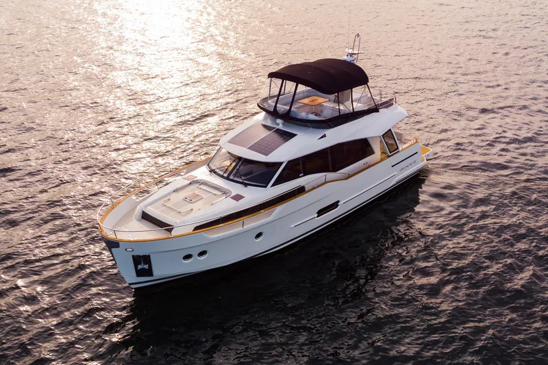 Tui Yacht Photos Pics 2023 Greenline 48 Fly yacht cruising on calm waters at sunset.