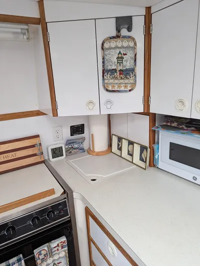  Yacht Photos Pics Compact kitchen area in a 2000 Manta 42 boat, featuring white cabinets and a microwave.