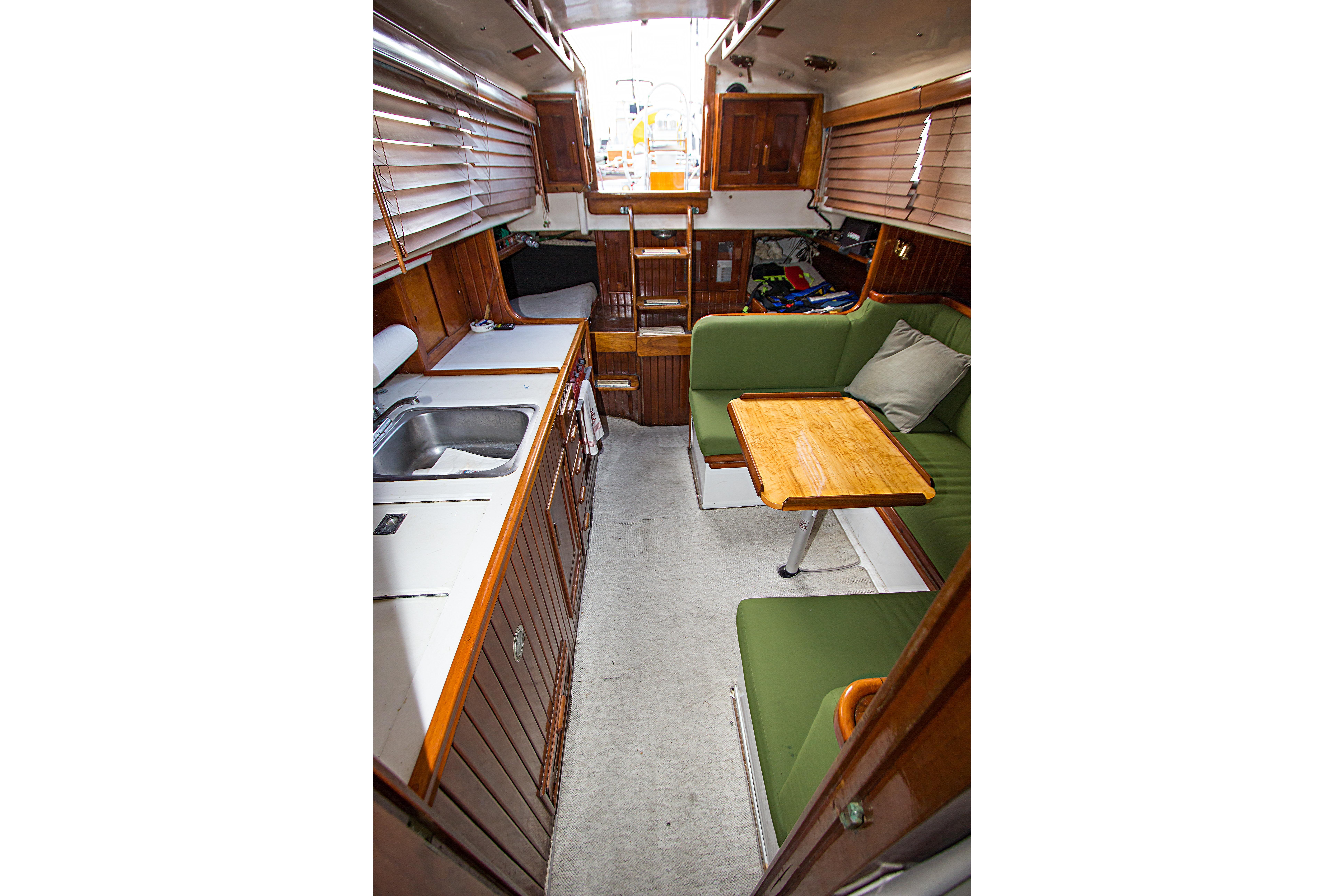 Interior of a 1965 Pearson Vanguard sailboat with green seating and wooden cabinetry.