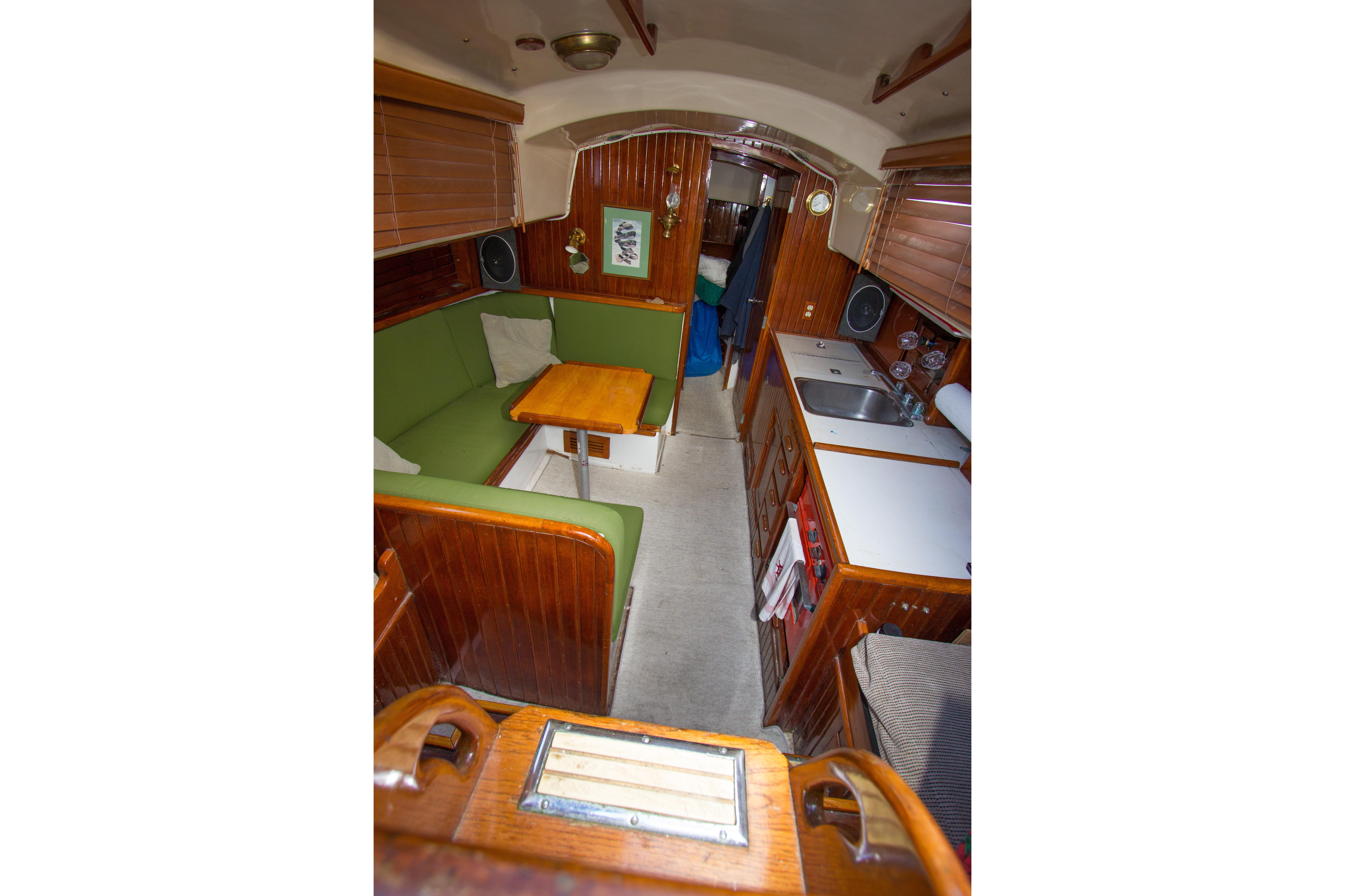 Interior of a 1965 Pearson Vanguard sailboat with green seating and wooden cabinetry.