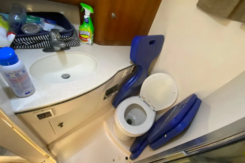  Yacht Photos Pics 2001 Intrepid 377 Walkaround boat bathroom with sink, toilet, and cleaning supplies.