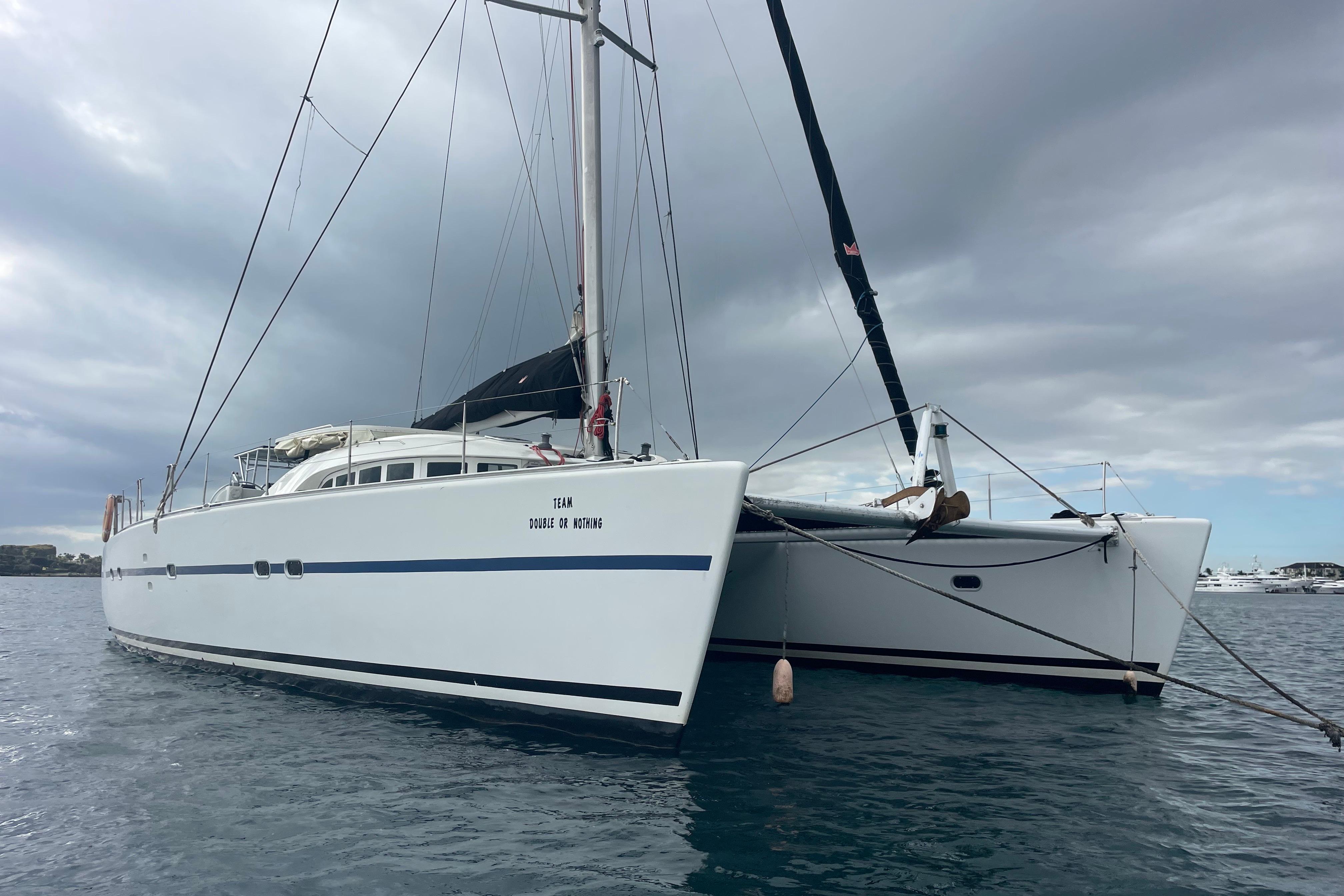 2004 Lagoon 570 catamaran anchored under cloudy skies on calm water.