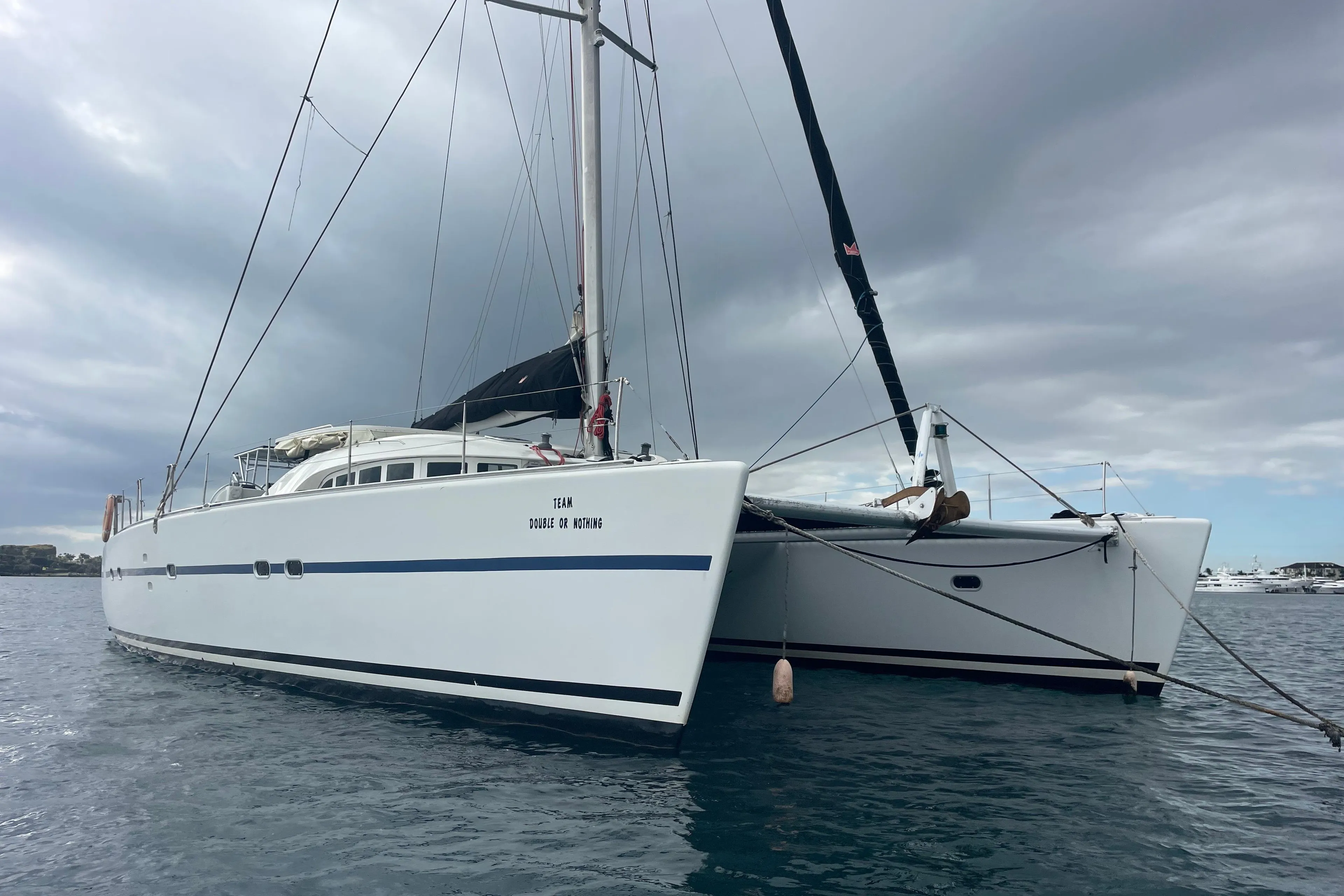 2004 Lagoon 570 catamaran anchored under cloudy skies on calm water.