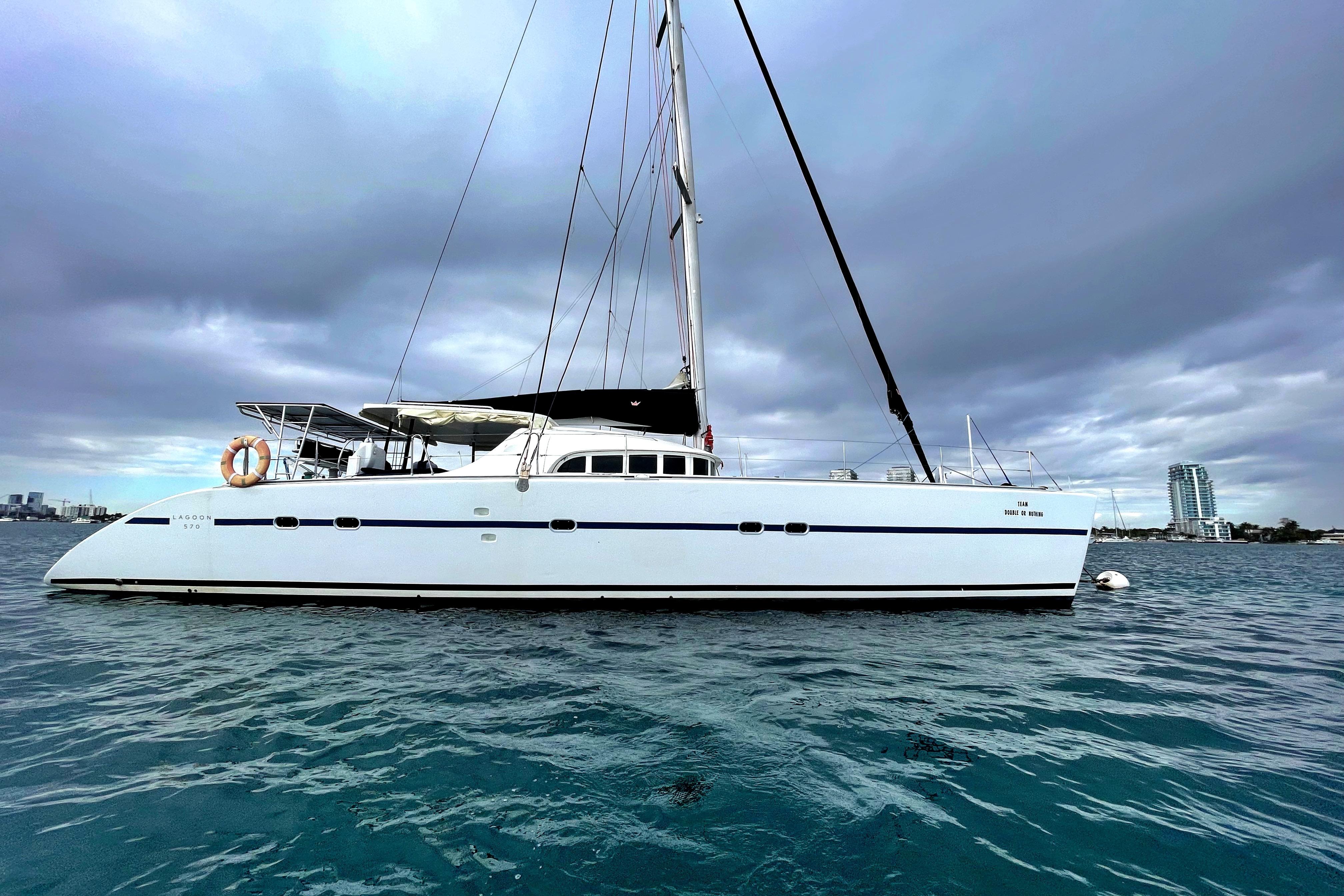 2004 Lagoon 570 catamaran on calm water under cloudy skies.