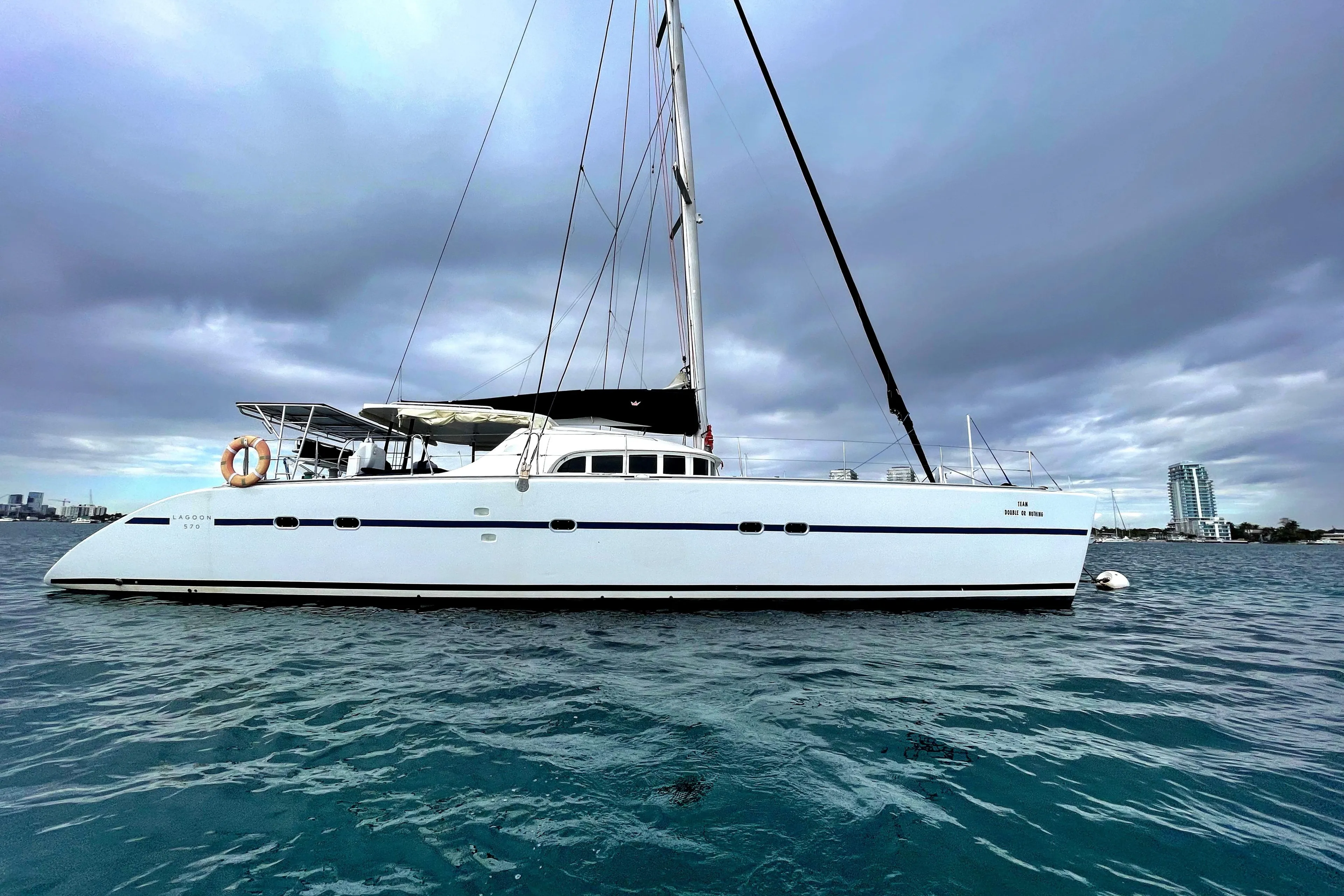 2004 Lagoon 570 catamaran on calm water under cloudy skies.