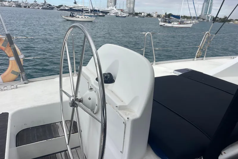 Futuna Yacht Photos Pics Steering wheel of 2004 Lagoon 570 yacht with ocean and boats in background.