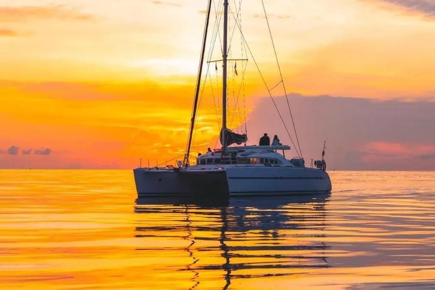 Lagoon 570 catamaran sailing at sunset, 2004 model, tranquil ocean scene.