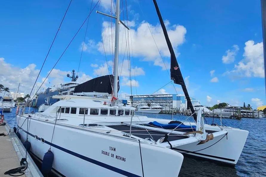 2004 Lagoon 570 catamaran docked at marina under clear blue sky.