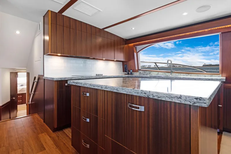  Yacht Photos Pics Luxurious kitchen interior of 2016 Hatteras 63GT yacht with wooden cabinetry and granite countertops.
