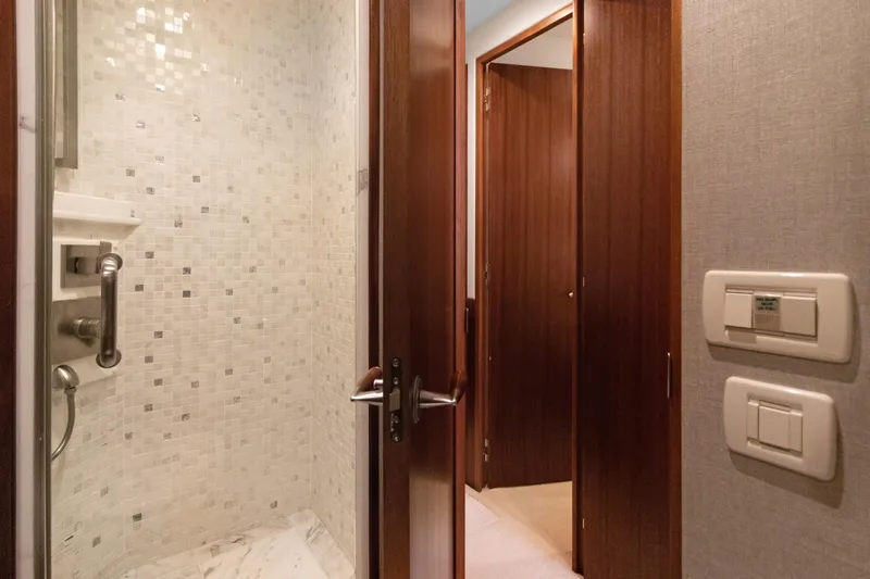  Yacht Photos Pics Interior of 2016 Hatteras 63GT yacht, featuring a modern bathroom with wooden doors and mosaic tiles.