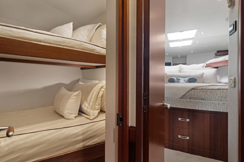  Yacht Photos Pics Interior of 2016 Hatteras 63GT yacht featuring cozy bunk beds and elegant wood finishes.