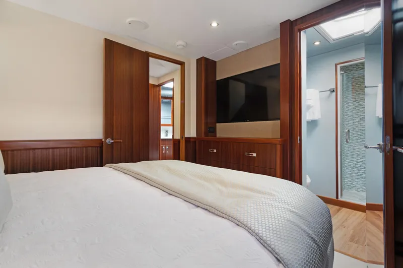  Yacht Photos Pics Luxurious bedroom interior of 2016 Hatteras 63GT yacht with modern wood finishes and flat-screen TV.