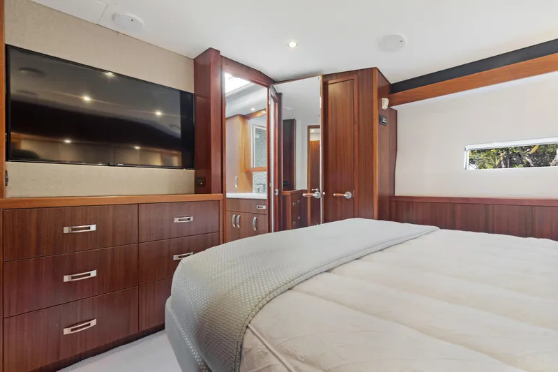  Yacht Photos Pics Luxurious bedroom interior of 2016 Hatteras 63GT yacht with modern furnishings and large TV.