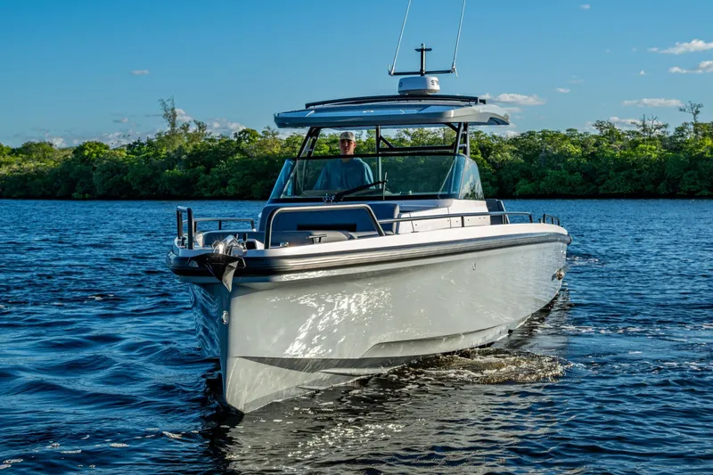 Chye-lukh Yacht Photos Pics 2021 Axopar 37 boat cruising on a sunny day, surrounded by lush greenery.