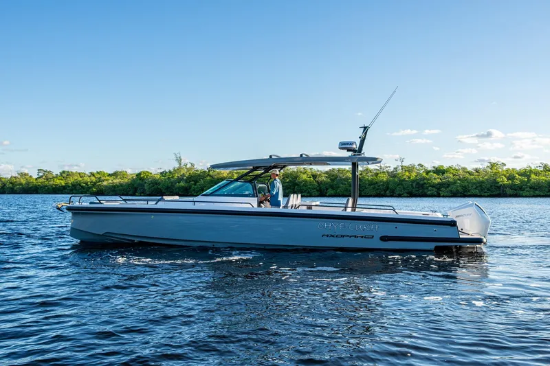 Chye-lukh Yacht Photos Pics 2021 Axopar 37 boat cruising on a sunny day, surrounded by lush greenery.