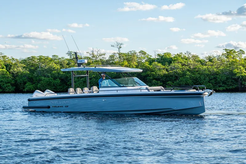 Chye-lukh Yacht Photos Pics 2021 Axopar 37 boat cruising on a calm lake with lush green trees in the background.