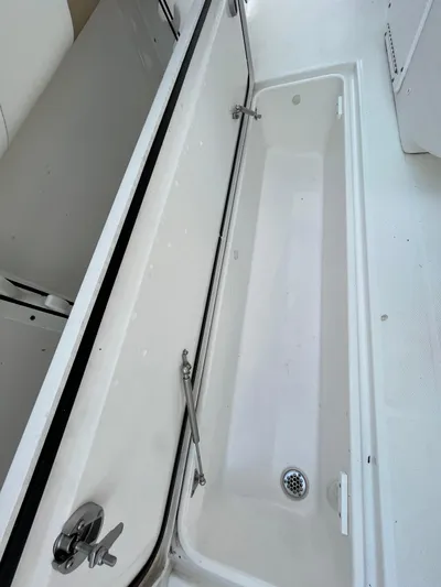  Yacht Photos Pics 2022 Edgewater 285CC boat storage compartment with drain, open and empty.