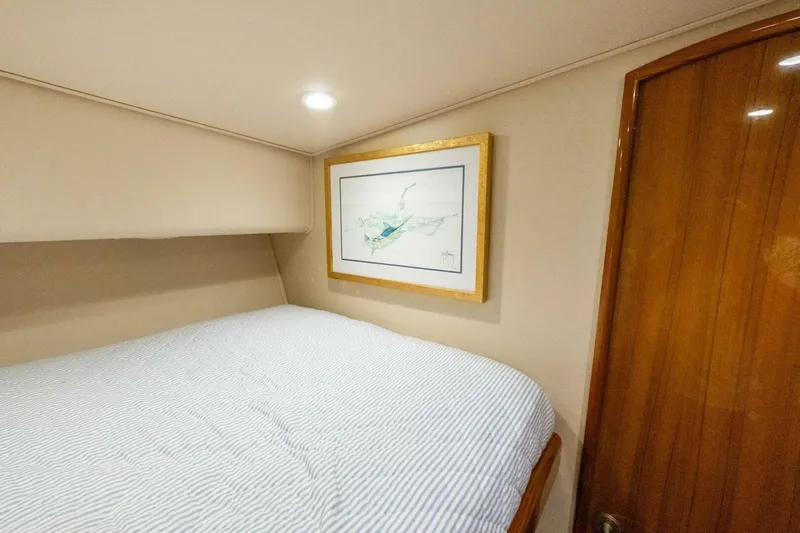 Terrabbean Yacht Photos Pics Cozy bedroom interior of 2015 Viking 52 Open yacht with framed artwork and wooden door.