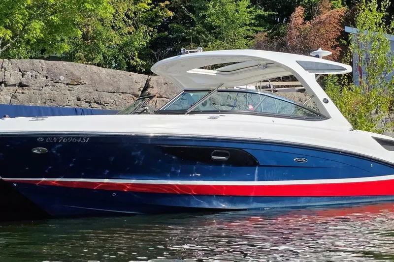  Yacht Photos Pics 2019 Sea Ray 350 SLX boat with blue and red accents, docked near rocky shoreline.