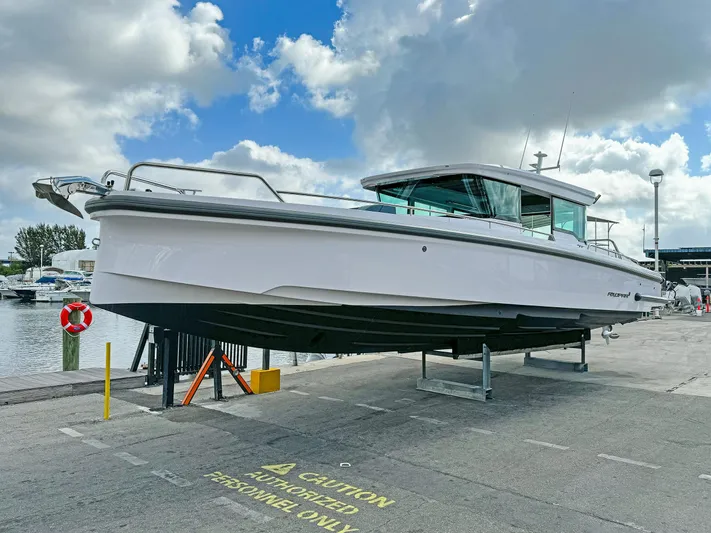  Yacht Photos Pics 2024 Axopar 37XC CROSS CABIN boat on dock under cloudy sky.