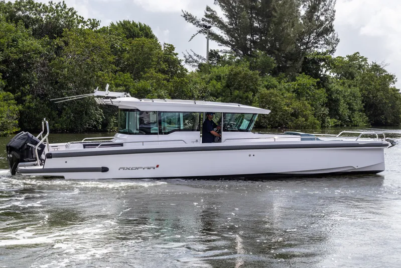  Yacht Photos Pics 2024 Axopar 37XC CROSS CABIN cruising on a river, surrounded by lush greenery.