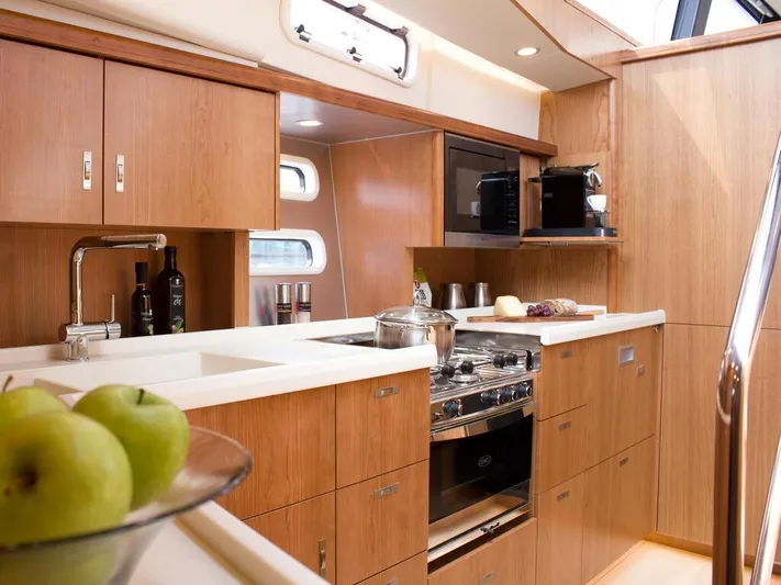  Yacht Photos Pics Luxurious 2025 Moody 54 DS yacht kitchen with modern appliances and wooden cabinetry.