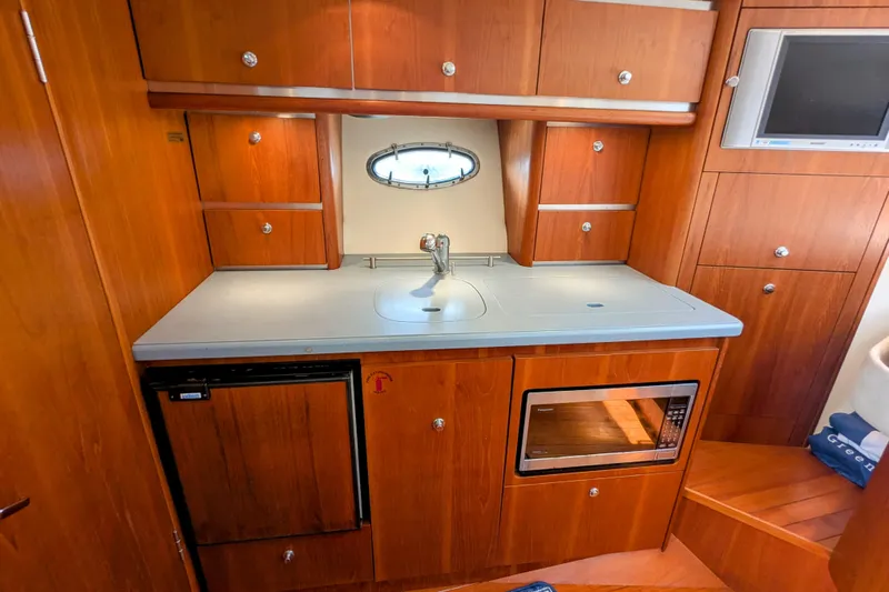  Yacht Photos Pics 2005 Tiara Yachts 3200 Open galley with wood cabinetry, sink, microwave, and mini-fridge.
